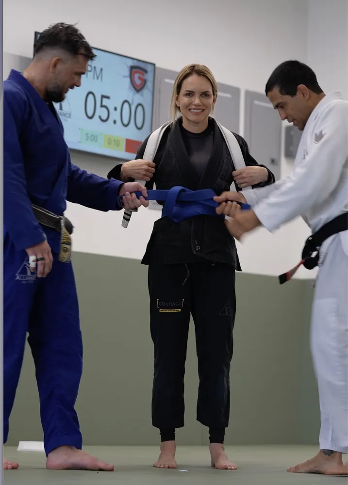 Coaches tying a new blue belt on a student at a promotion ceremony