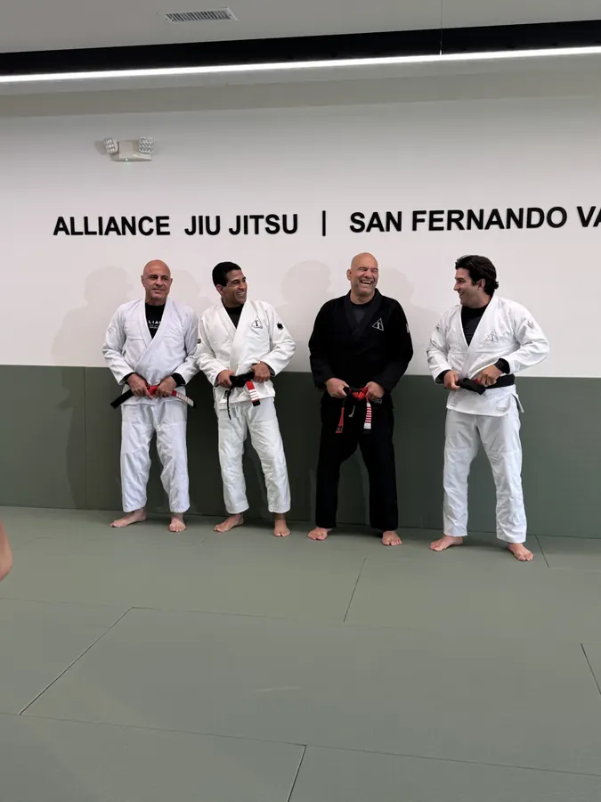 Black belts in front of the academy wall